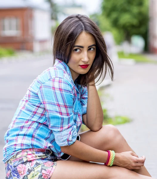 Krásná brunetka, která sedí na silnici módní žena v barevné košili — Stock fotografie