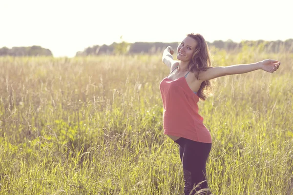 Young beautiful pregnant woman holding tummy smiling, in red a light summer dress, happy on meadow the grass — Stock Photo, Image