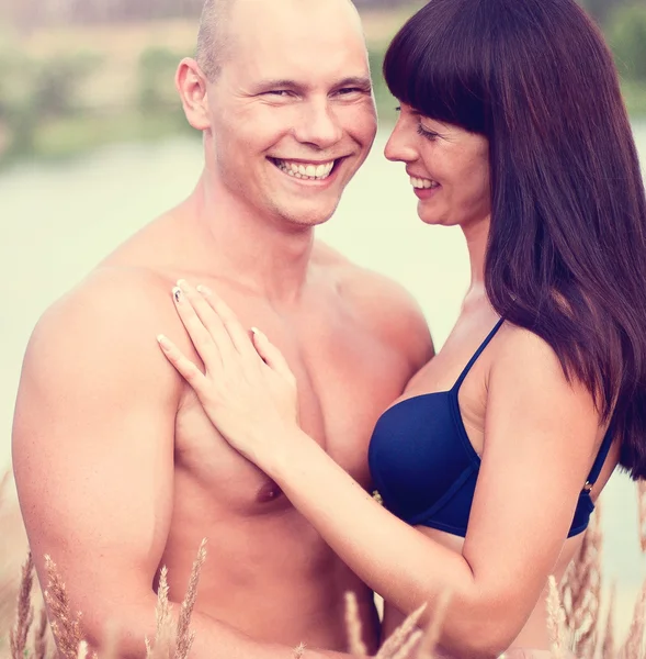 Glückliches Paar lächelt Sommer in Feld auf einem Hintergrund des Sees — Stockfoto