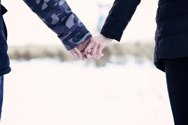 Νεαρό ζευγάρι σε εξωτερικούς χώρους, κρατώντας τα χέρια στο χειμερινό πάρκο. Αγγίζοντας μια νεαρών οικογενειών. — Φωτογραφία Αρχείου