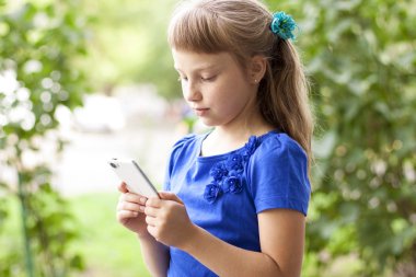 Küçük kız yaz park mavi elbiseli telefonla konuşuyor. Sarışın