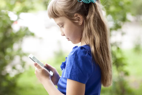 小さな女の子夏公園が青いドレスで、電話で話しています。金髪 — ストック写真