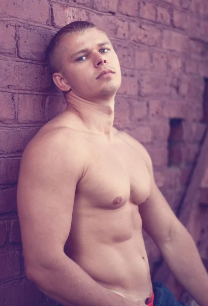 Bodybuilder at a brick wall — Stock Photo, Image