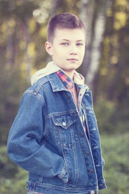 Genç çocuk parkı çayır güneşli bir gün, kot ceket standları, mesafe içine gömlek görünüyor