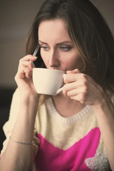 Mladá dívka, sedící v kavárně s šálkem kávy. — Stock fotografie