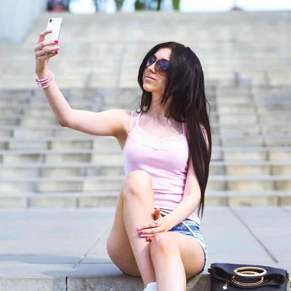 Girl sitting on stairs, in the street makes your phone beautiful self — Stock Photo, Image
