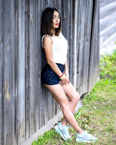 Όμορφη κορίτσι στέκεται στο φράχτη στυλ γυναίκα μόδας καλοκαίρι υπαίθρια αναπαύσεως ξύλινο — Φωτογραφία Αρχείου