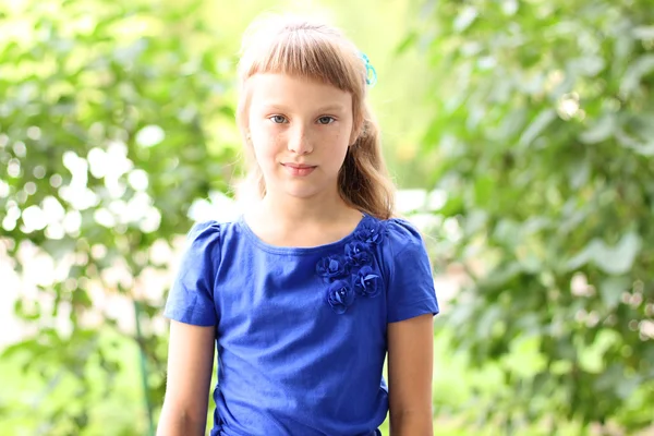 Weinig meisje blauwe jurk heldere zonnige zomer dag park onder groene struiken, op zoek idee concept van teen fashion stijl, vormt voor portret — Stockfoto