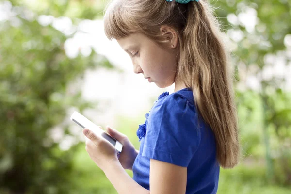 小さな女の子夏公園が青いドレスで、電話で話しています。金髪 — ストック写真