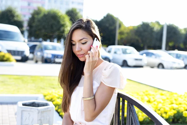 Gyönyörű nő beszél a telefonon, egy ragyogó napsütéses nap, pad, divat-stílus városi élet. barátja, fia, lánya, férje — Stock Fotó