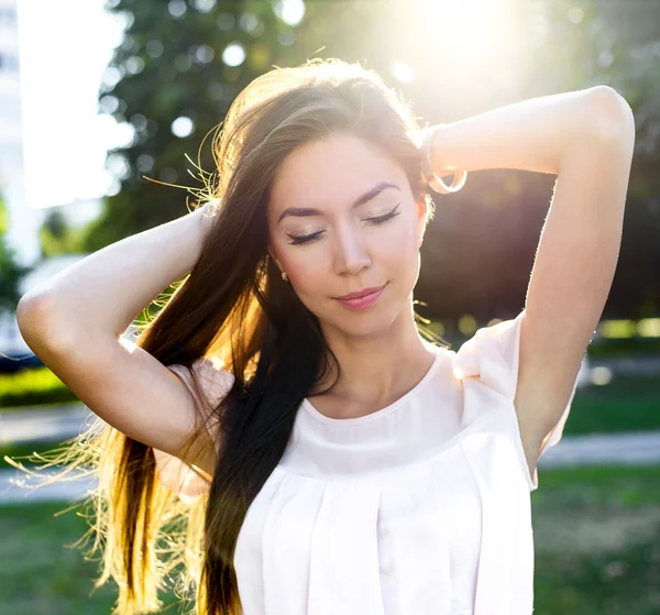 Retrato de uma bela morena no parque segurando o cabelo desfrutar de suas férias, em luz solar brilhante. Estilo de moda vida urbana, sonhos emocionais. Verão ao ar livre . — Fotografia de Stock