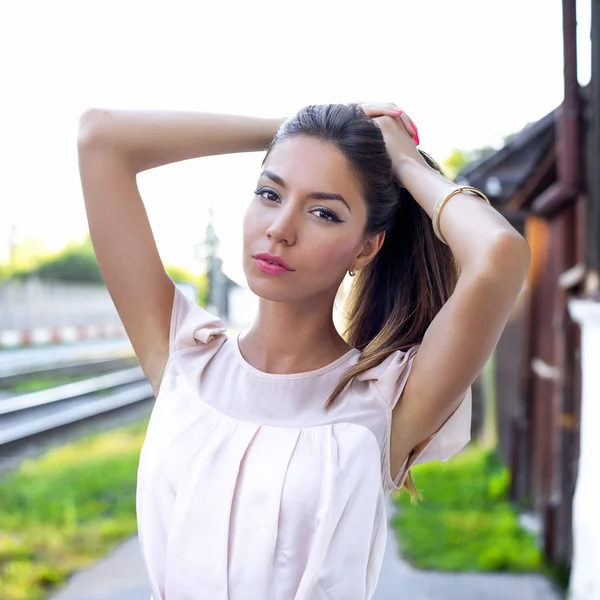 Menina doce bonita endireita o cabelo no verão na cidade, estilo de vida da moda, em um vestido rosa. Morena. Descansar ao ar livre . — Fotografia de Stock