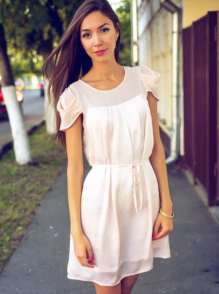 Belle fille brune en plein air, posant dans une rue de la ville, style de mode, en robe rose, style de vie, business happy tanned woman urban life . — Photo