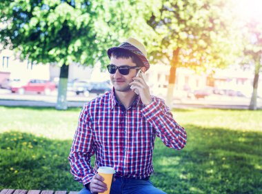 telefonu, akıllı telefon, yaz, işadamı tatil kavramı üzerinde konuşan adam bardaklarda, tişört ve kot pantolon. Şehir bir yaşam tarzı. Park Caddesi.