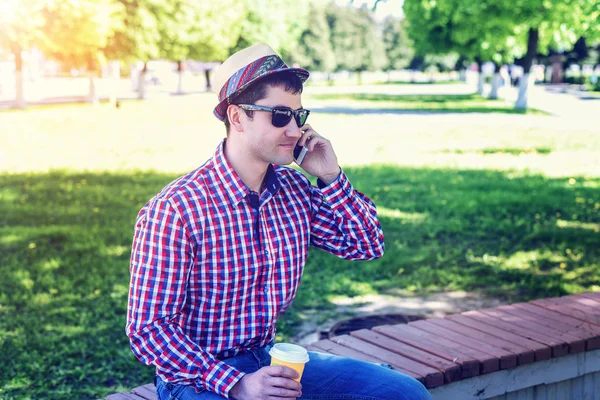 Homem de camisa e jeans óculos, falando ao telefone, smartphone, o conceito de verão, férias de homem de negócios. Estilo de vida da cidade. a rua no parque . — Fotografia de Stock