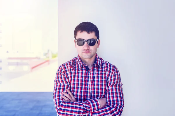 O homem no verão contra a parede, óculos, diretor executivo sério, em jeans e uma camisa, dia ensolarado brilhante. A ideia do conceito de empresário na cidade. Estilo de vida, retrato — Fotografia de Stock