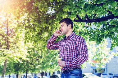 telefonu, akıllı telefon, yaz, işadamı tatil kavramı üzerinde konuşan adam bardaklarda, tişört ve kot pantolon. Şehir bir yaşam tarzı. Park Caddesi.