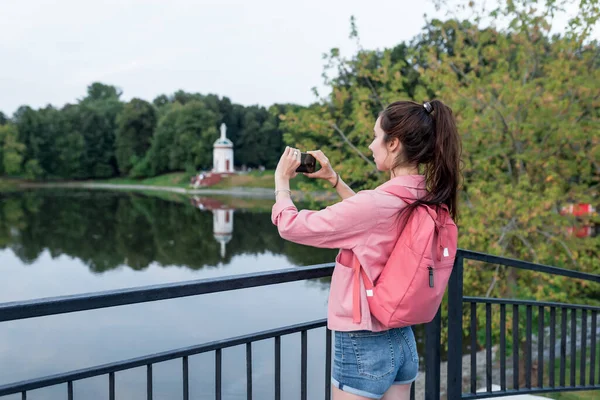 Wanita di musim panas di kota dekat danau, sungai dan kolam, fotografi lanskap pada smartphone, merekam video di Internet, aplikasi kamera smartphone. Ruang kosong untuk menyalin teks. — Stok Foto