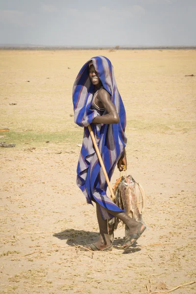 Menino carrega os peixes secos do Lago Turkana, Quênia Imagens Royalty-Free