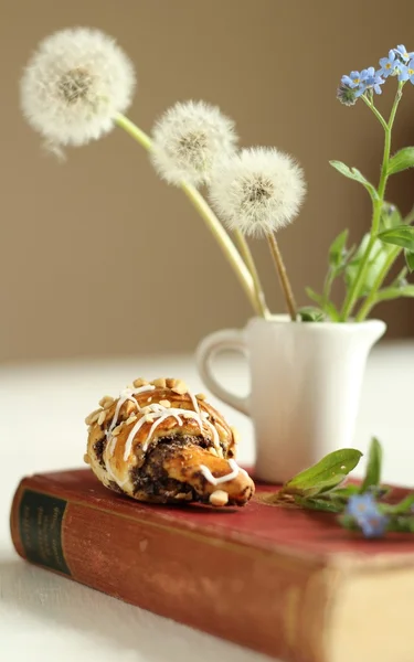 Karaf met bloemen forget-me-not op vintage boek en croissants — Stockfoto