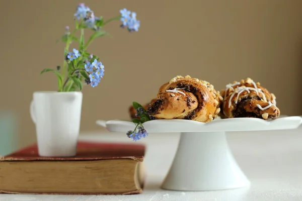 Krug mit Blumen vergiss-mich-nicht auf dem Vintage-Buch und Croissants — Stockfoto