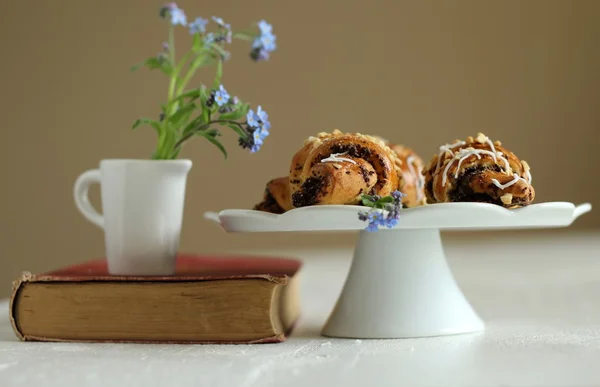 Krug mit Blumen vergiss-mich-nicht auf dem Vintage-Buch und Croissants — Stockfoto