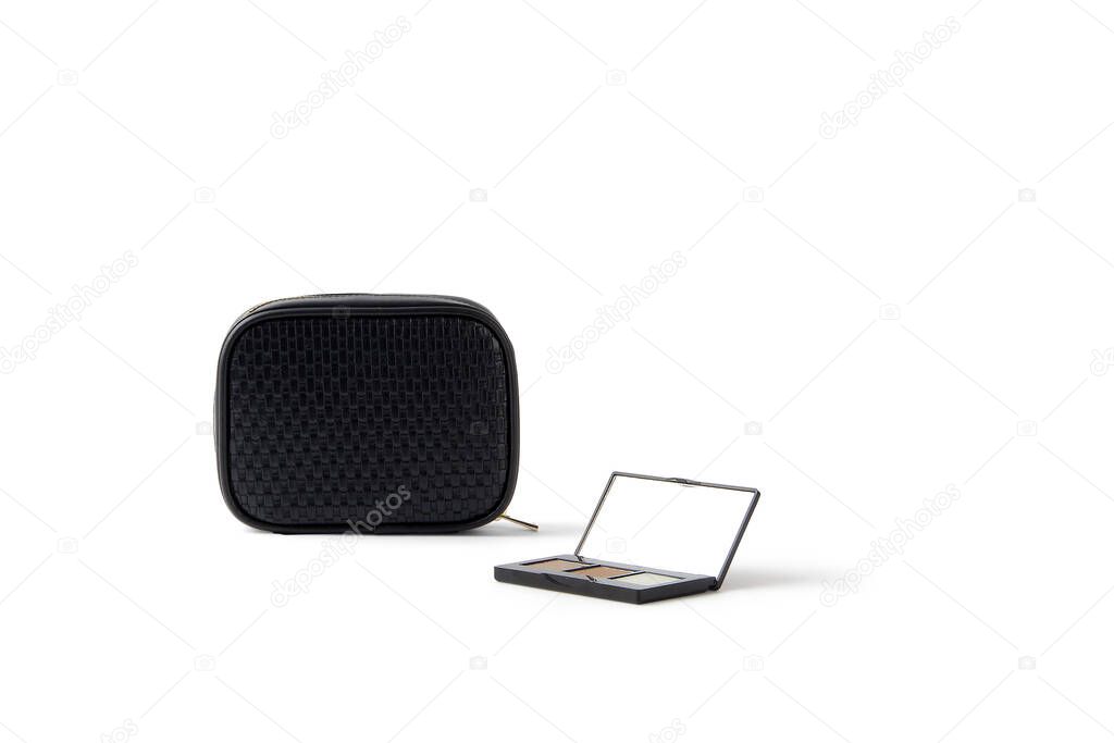 Isolated black bag near a eyeshadow box mirror on a white background with copy space. Cosmetic products on a white background.