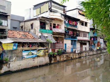 Tambora, jakarta, Endonezya - (04-03-2021): Yoğun nüfuslu bir bölgedeki kirli bir nehrin önündeki varoş evi