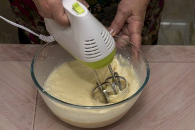 Kadınların elleri hamuru farklı malzemelerle yoğuruyor. Süt, un, tereyağı, şeker ve ev yapımı krepler için yumurta..