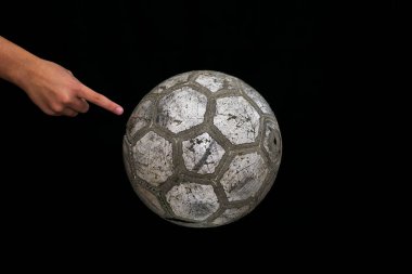 Siyah arka planda bir gencin elinde eski futbol topu.