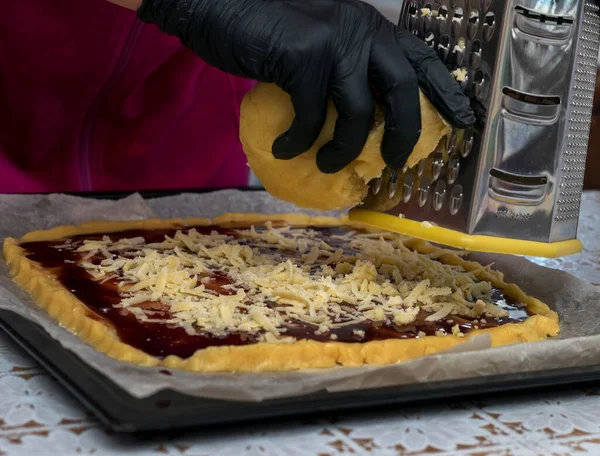 Шеф-кондитер в черных перчатках потирает тесто о железную терку для приготовления венского печенья.. — стоковое фото