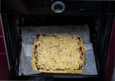 Siyah eldivenli kadın elleri pişirmek için fırına tatlı bir pasta koydu..