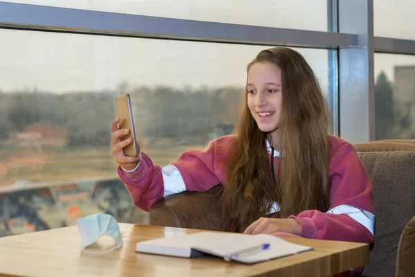 Une jeune adolescente tient un blog, parle au téléphone, prend des notes dans un carnet. Images De Stock Libres De Droits
