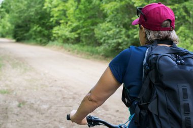 Güneşli bir günde parkta bisikletli bir kız yürüyor..