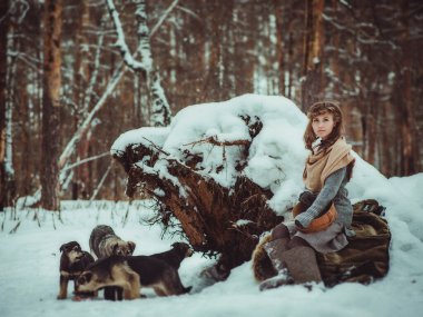 Genç bir kız, kışın bir çam ormanında yalnız başına keçeli çizme ve basit köylü kıyafetleri giyerek başıboş köpekleri beslemeye geldi.