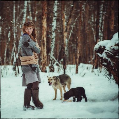 Genç bir kız, kışın bir çam ormanında yalnız başına keçeli çizme ve basit köylü kıyafetleri giyerek başıboş köpekleri beslemeye geldi.