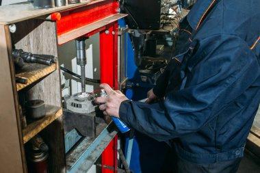 Araba tamirhanesinde çalışan bir işçi jeneratörü test eder ve tamir eder.