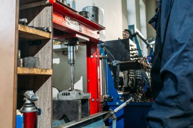 Araba tamirhanesinde çalışan bir işçi jeneratörü test eder ve tamir eder.