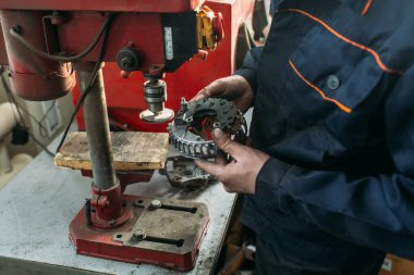 Araba tamirhanesinde çalışan bir işçi jeneratörü test eder ve tamir eder.