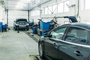 Otomobil atölyesinde kaputu açık bir servis arabası var.