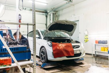 Otomobil atölyesinde kaputu açık bir servis arabası var.