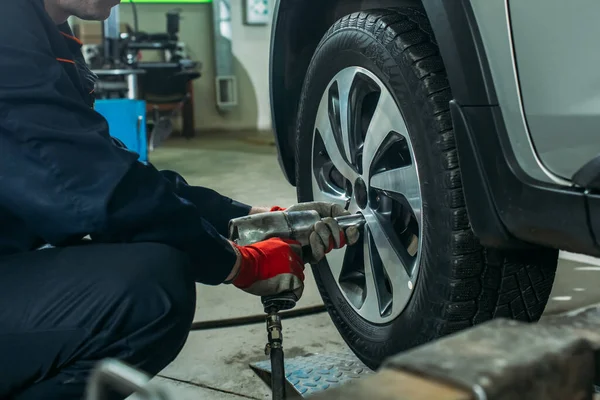 the tire fitting process in the garage, the worker removes the wheel, makes the tire fitting and puts the wheel