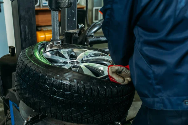 the tire fitting process in the garage, the worker removes the wheel, makes the tire fitting and puts the wheel