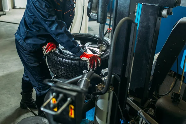 the tire fitting process in the garage, the worker removes the wheel, makes the tire fitting and puts the wheel