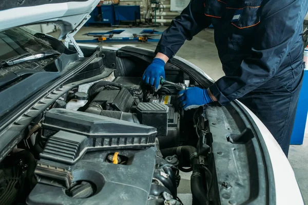 the process of replacing the car battery in the garage, a worker removes the old battery, replaces and tests a new battery.