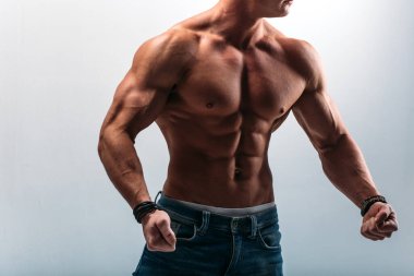 Güçlü bünyesi olan genç bir adam güzel gövdeli bir vücut geliştirici figürüne sahip. Beyaz bir arka planda stüdyoda çekim yapmak..