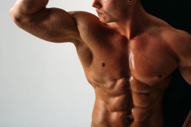 Güçlü bünyesi olan genç bir adam güzel gövdeli bir vücut geliştirici figürüne sahip. Stüdyoda siyah beyaz bir arkaplanda çekim yapmak. titreşimli ışık.