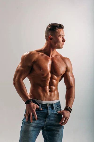 A young Man of strong constitution with a relief figure of a bodybuilder with a beautiful torso. Shooting in the studio on a white background.