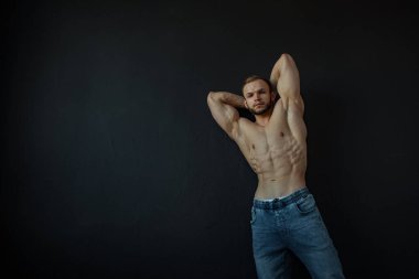 Güçlü bünyesi olan genç bir adam güzel gövdeli bir vücut geliştirici figürüne sahip. Stüdyoda siyah bir arkaplanda çekim yapmak..