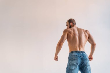 Güçlü bünyesi olan genç bir adam güzel gövdeli bir vücut geliştirici figürüne sahip. Beyaz bir arka planda stüdyoda çekim yapmak..